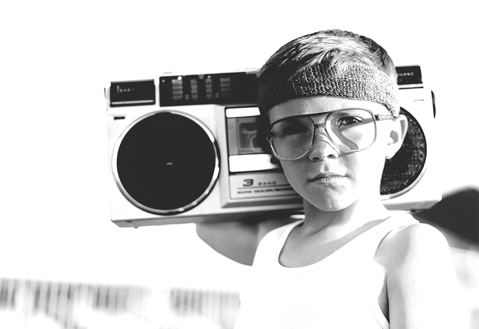 An old photo of a boy carrying a cassette player on his right shoulder.